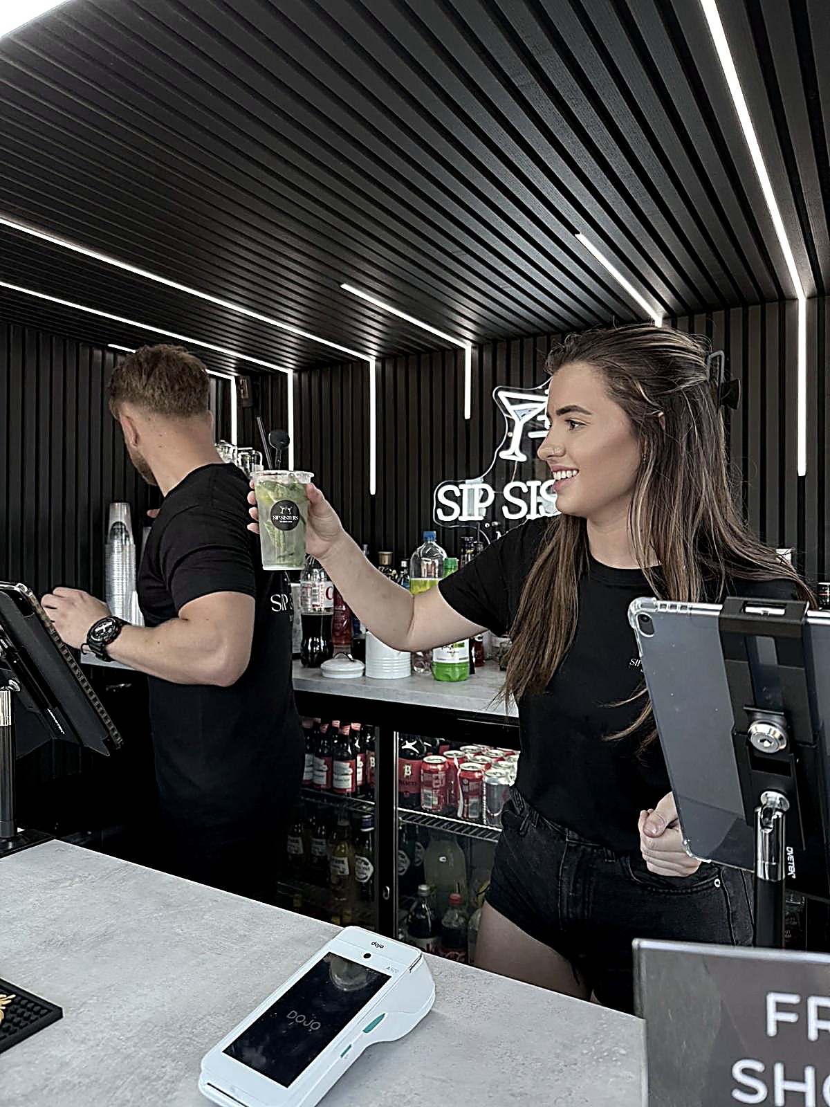 Sip Sisters team member serving a cocktail with a smile